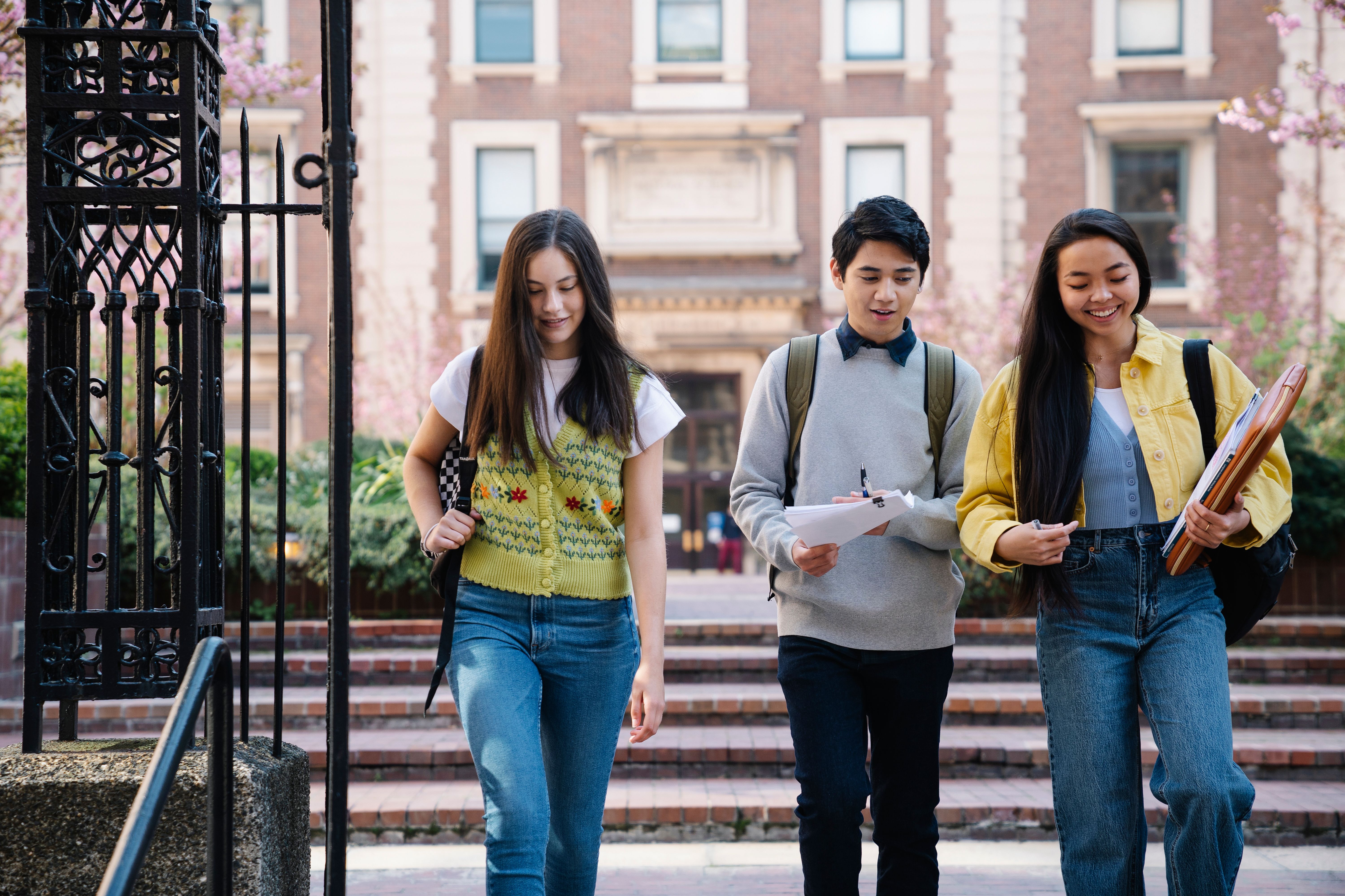 Three college students walking together across a university campus